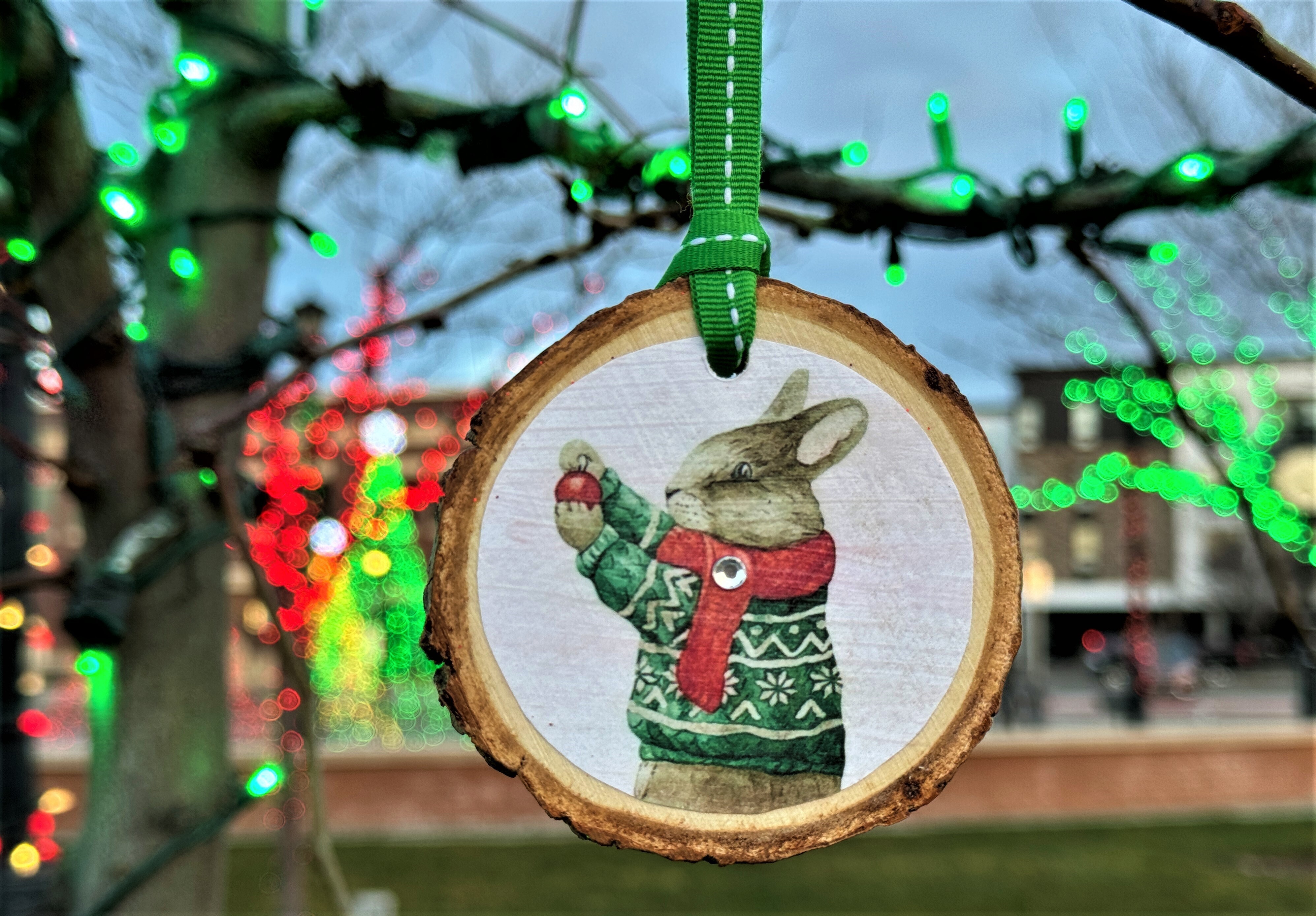 handmade ornament hanging from a tree with festive lights in background